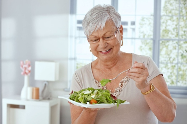 Пожилая дама ест салат